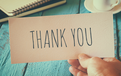 Bild Hand h�lt eine Karte mit der Aufschrift „Thank you“ �ber einem Holztisch