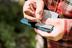 Ein Mann findet mit GPS einen Geocache im Wald. Geocaching-Spiel, Schatzsuche als Teamevent Ein Mann findet mit GPS einen Geocache im Wald. Geocaching-Spiel, Schatzsuche als Teamevent